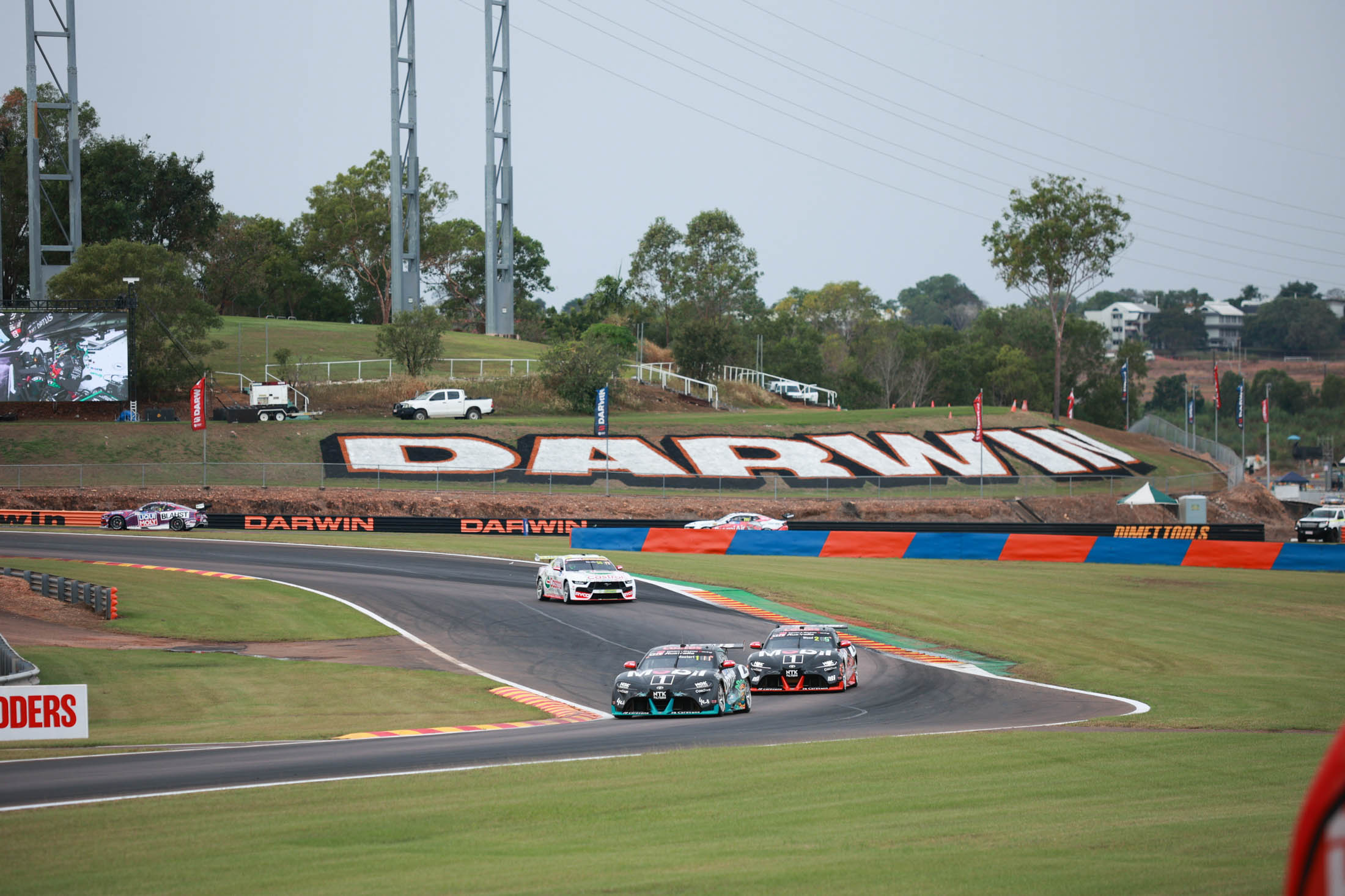 Supercars racing through a bend at Hidden Valley Raceway, with Darwin signage in the background.