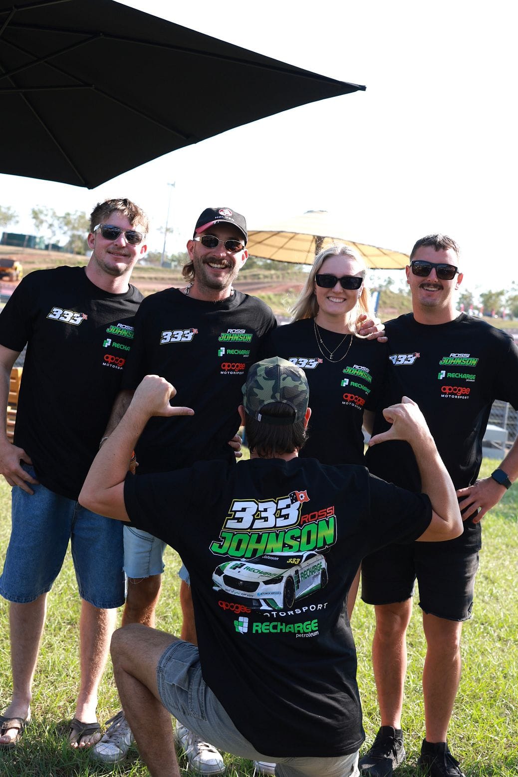 A group of fans in matching Ross Johnson Motorsport shirts pose together beside the track at Darwin Supercars.