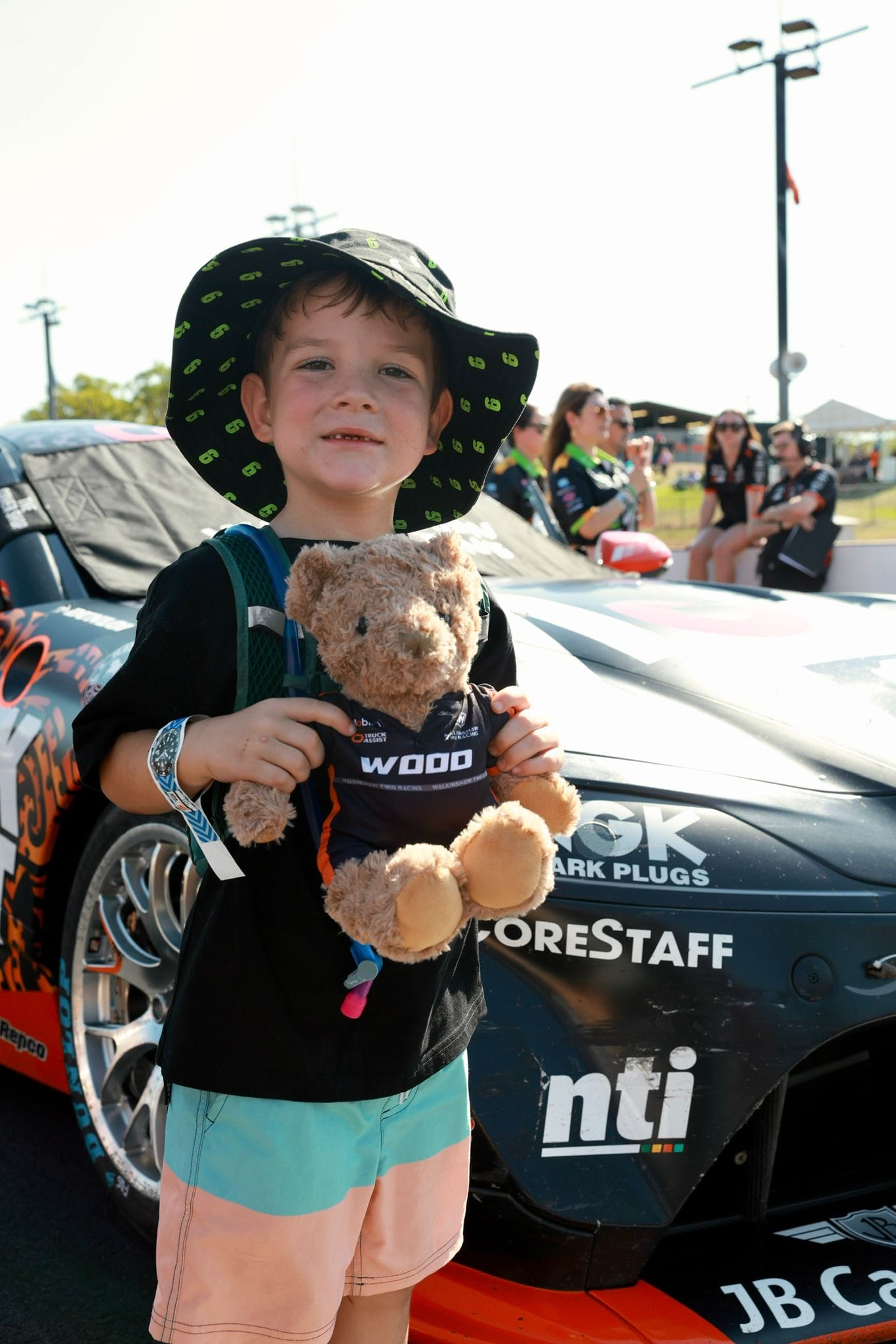 A young fan holds a teddy bear beside a Supercar during the Darwin Supercars grid walk.