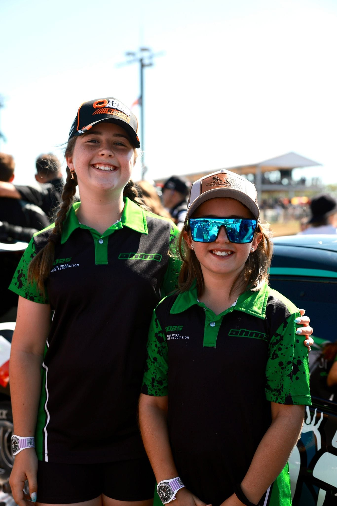 Two young motorsport fans smile in matching green and black team shirts at Darwin Supercars.