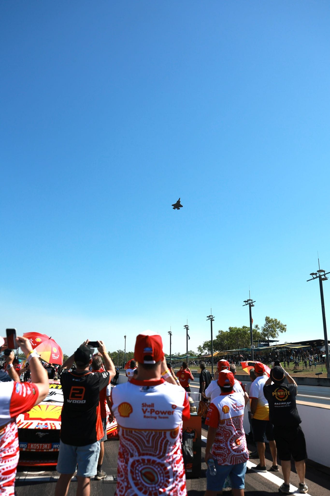 Fans and team members look up from pit lane as a jet flies over Hidden Valley Raceway.