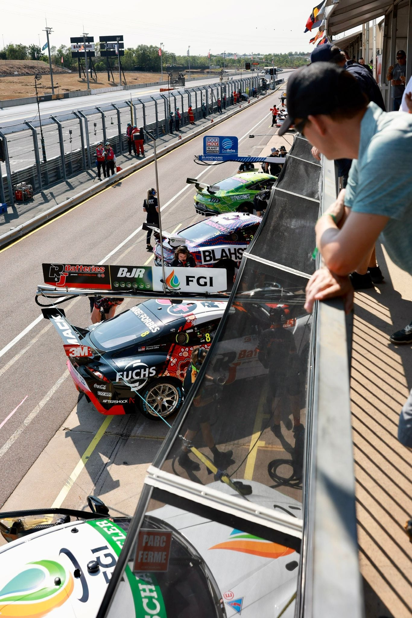 Spectators watch from above as Supercars line up in pit lane at Hidden Valley Raceway.