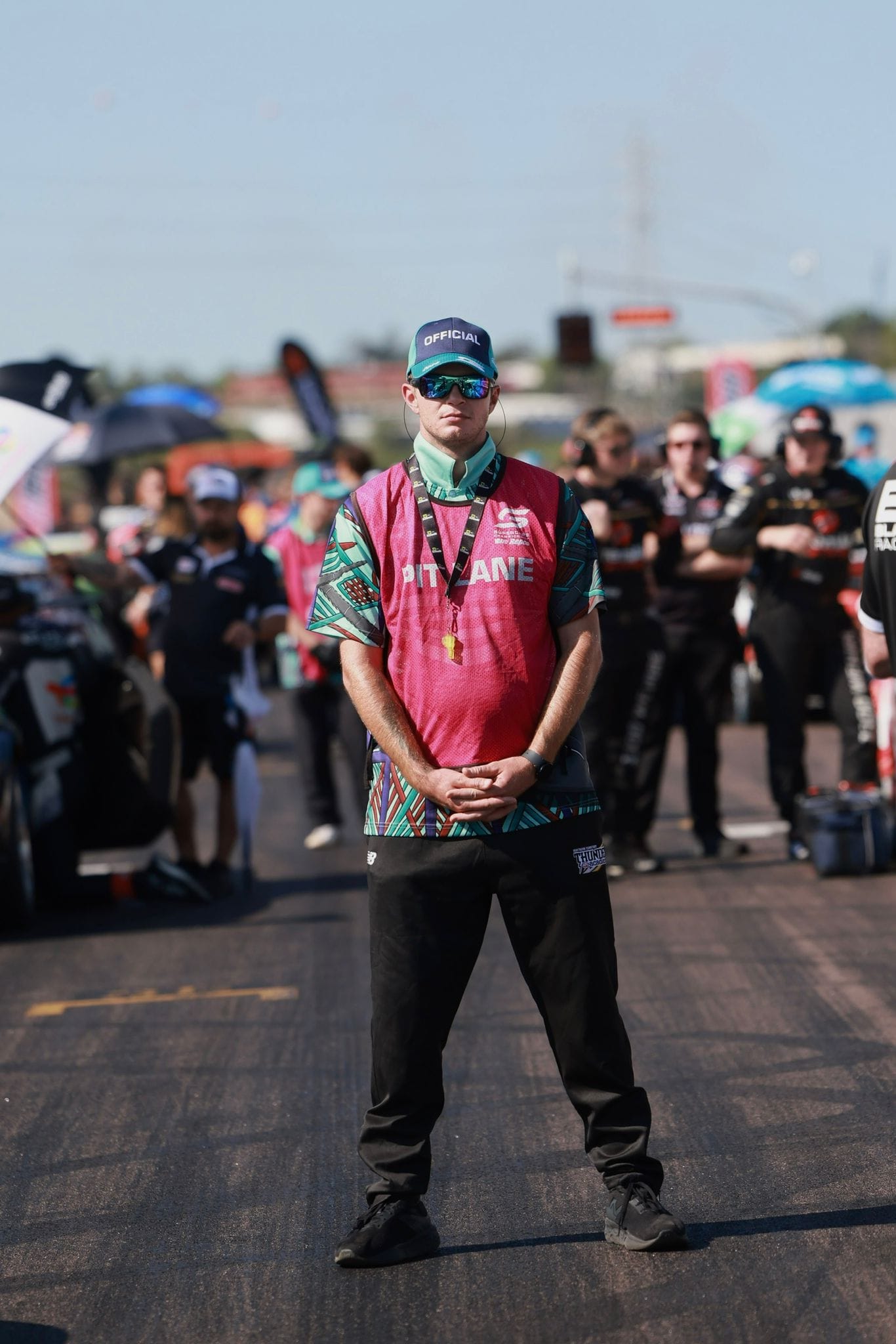 A pit lane official stands between Supercars on the grid at Hidden Valley Raceway.