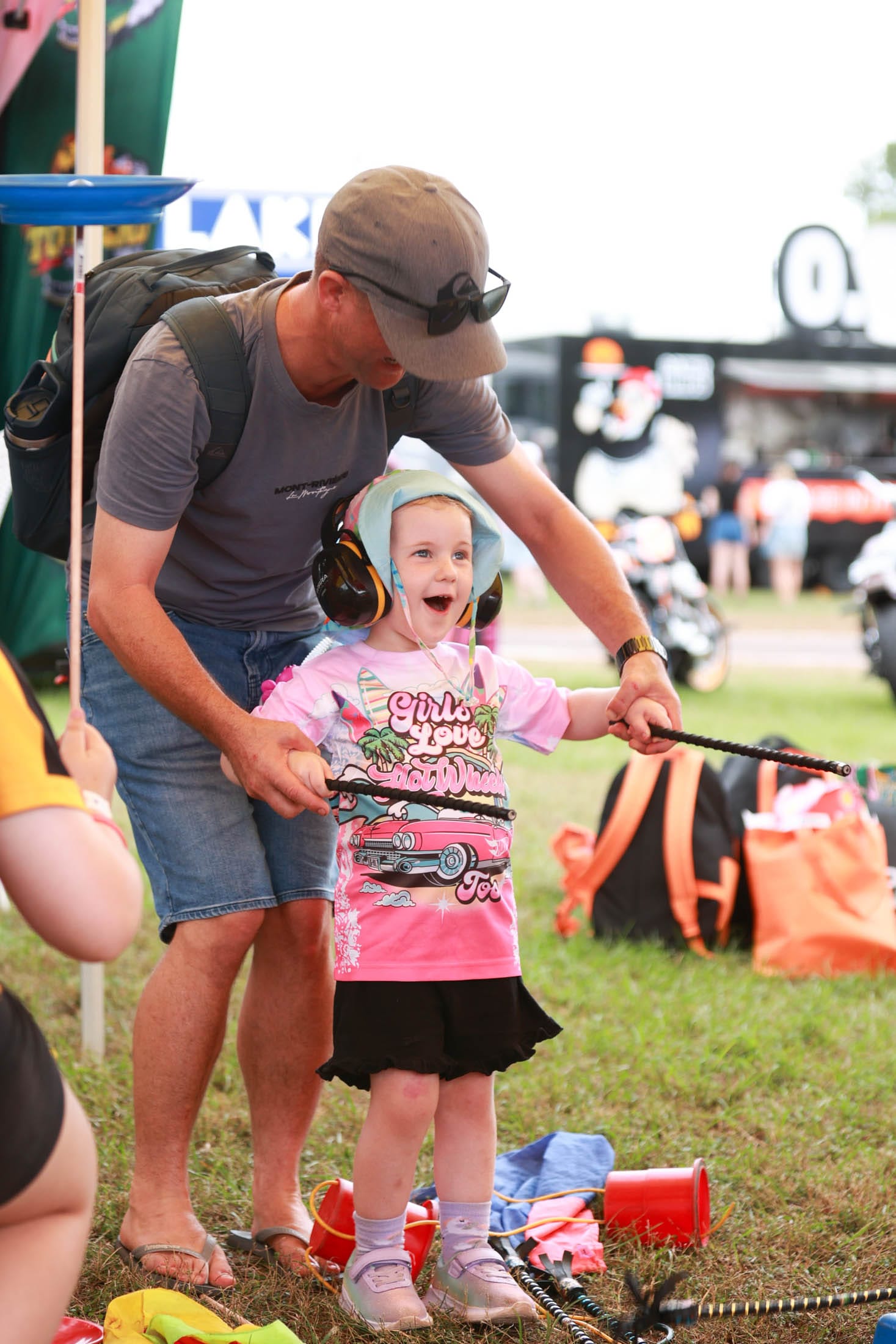 An adult helping a young child play with circus equipment in the Darwin Triple Crown family activity area.