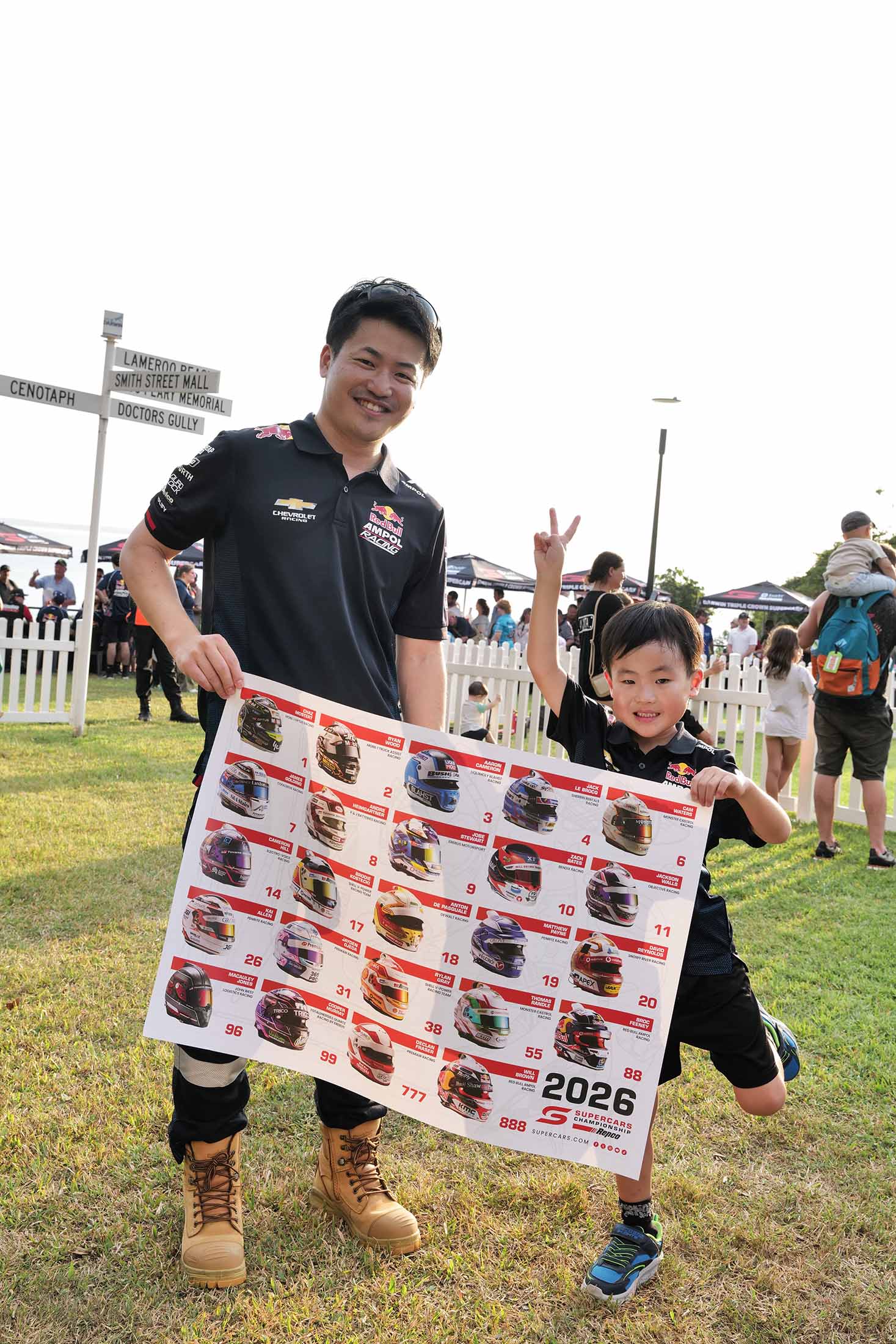 A Red Bull Ampol Racing fan and child holding a signed 2026 Supercars poster at Darwin Triple Crown.