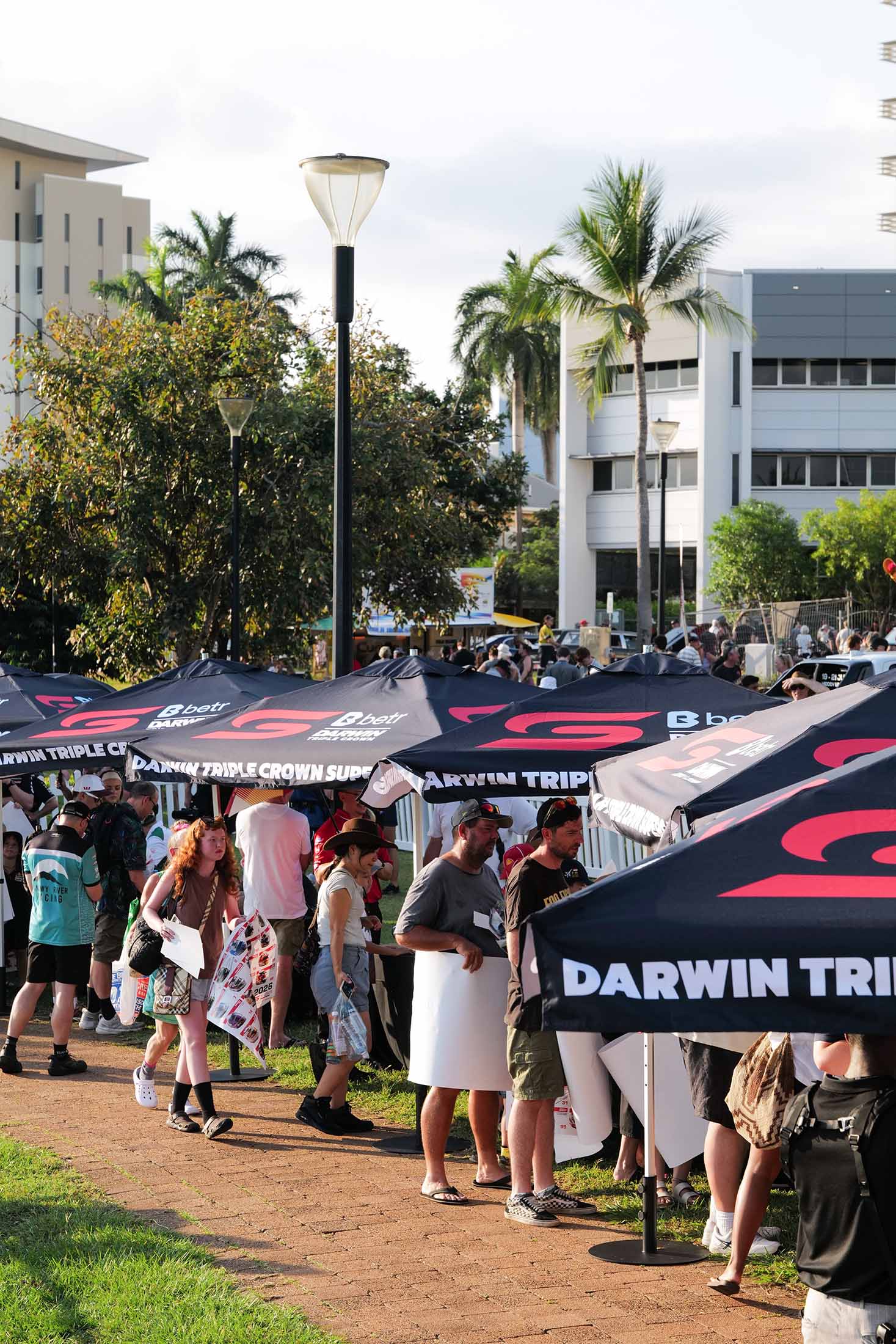 Crowds walking through the Darwin Triple Crown Supercars fan zone under branded event umbrellas.