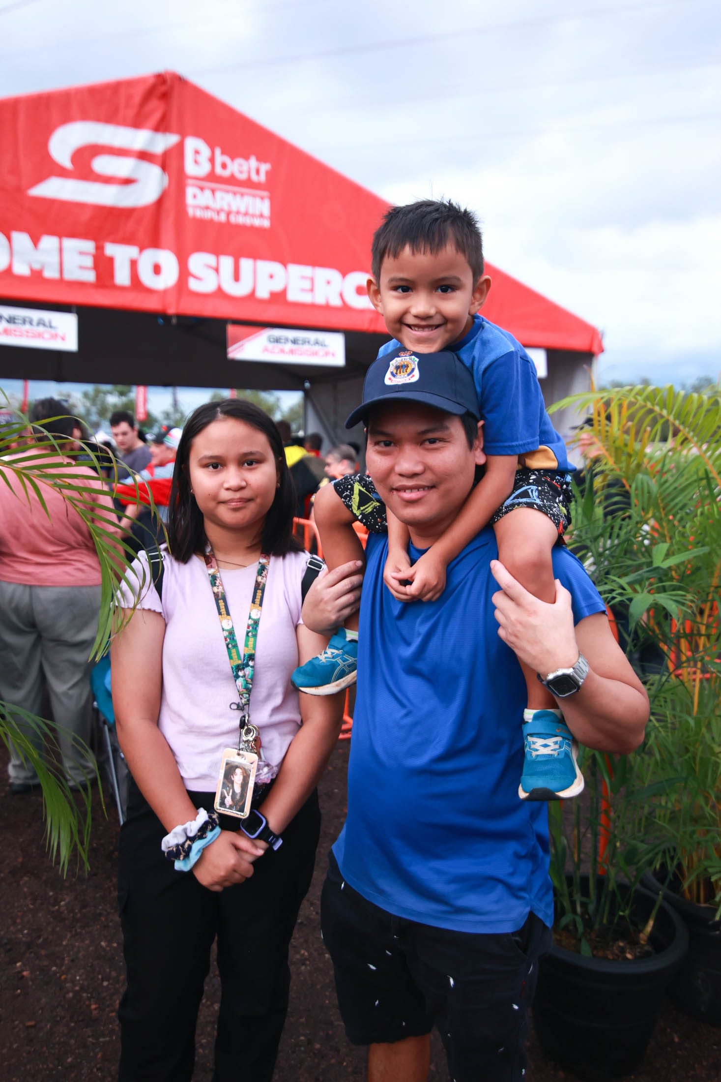 A man with a boy on his shoulders and a girl at the entry to Darwin Supercars