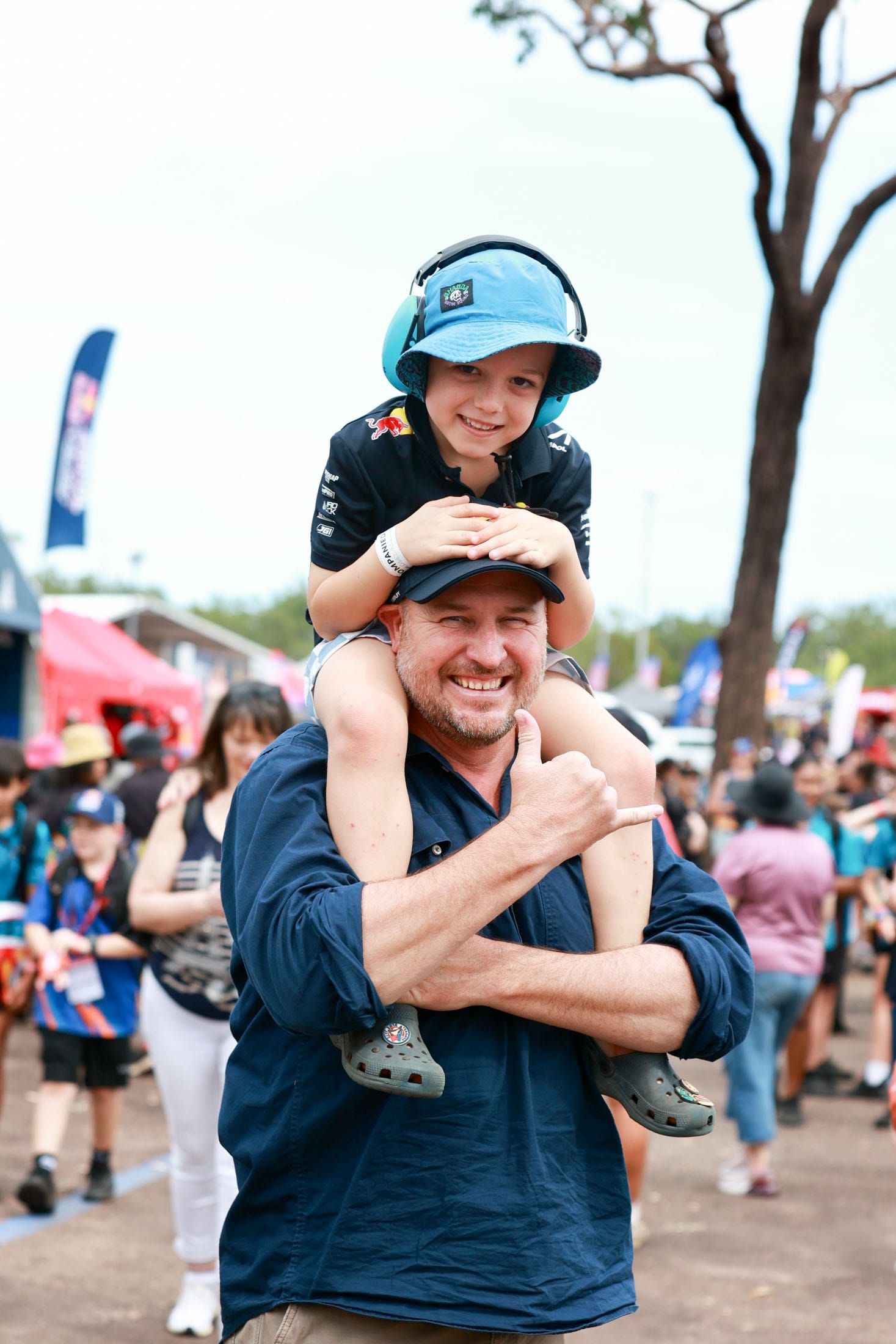 An adult and child smiling at the Darwin Triple Crown, with the child sitting on the adult’s shoulders.