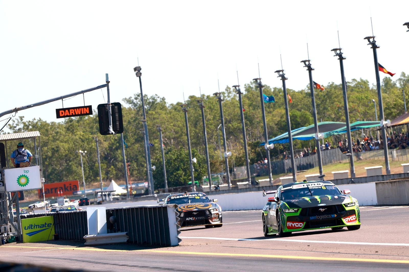 Supercars race down the main straight at Hidden Valley Raceway beneath the Darwin sign.