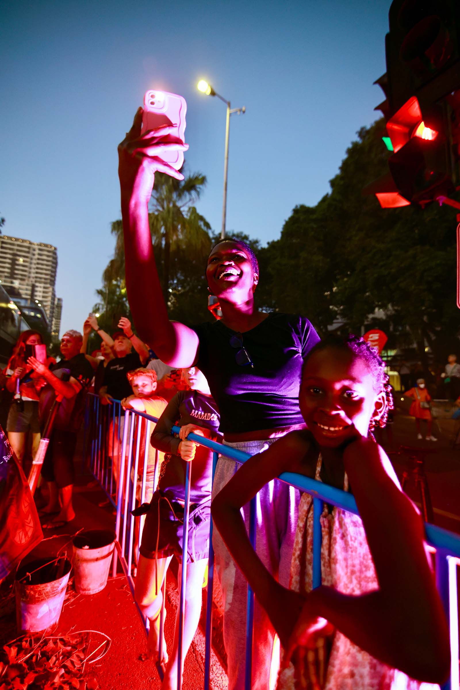 A person is taking a selfie with others at an event while holding up their phone.