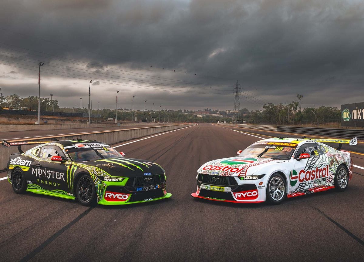 Monster Energy and Castrol Tickford Racing Supercars parked on track under dark storm clouds.