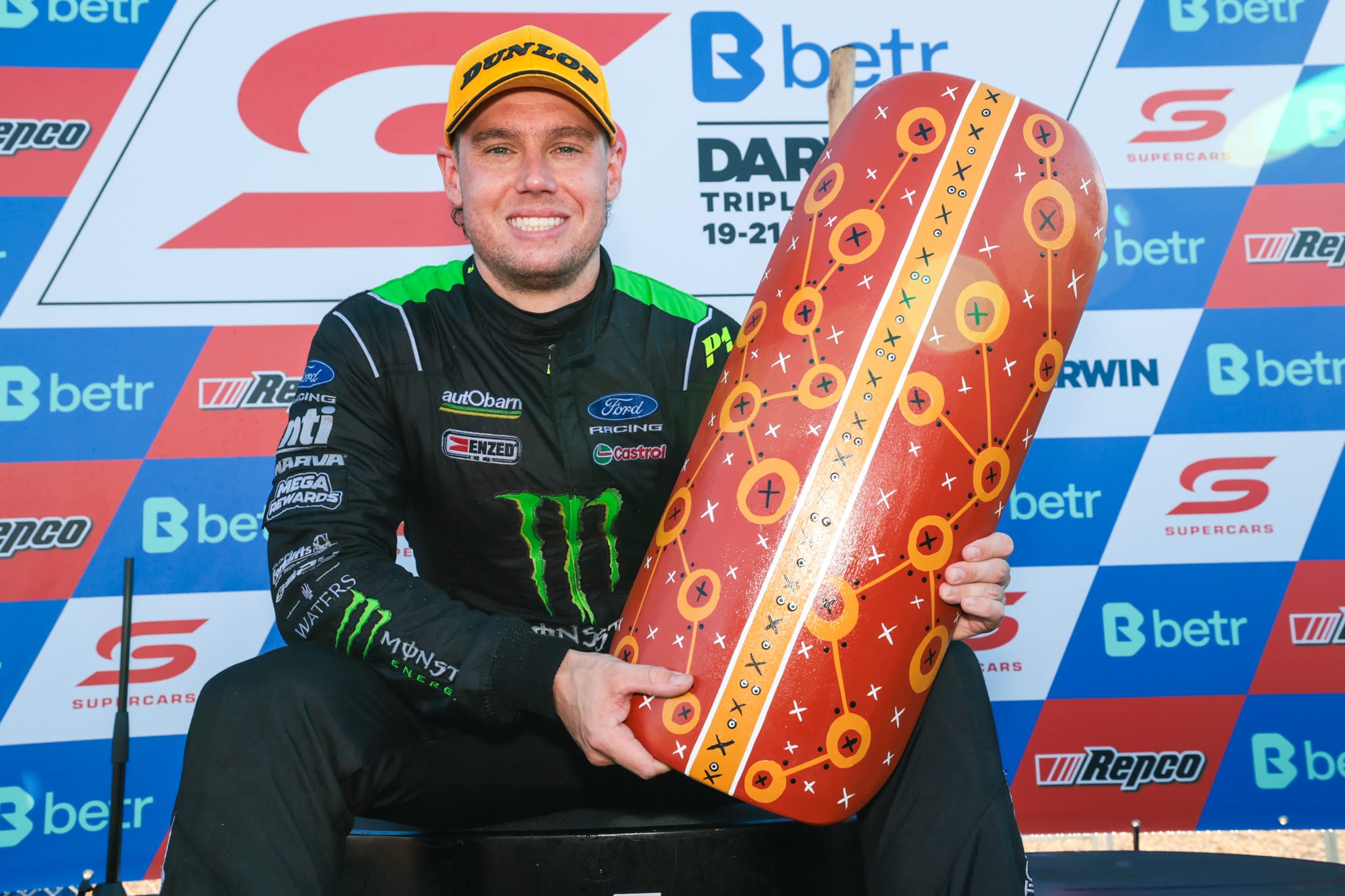 Cam Waters sits on the podium holding the Darwin Triple Crown trophy